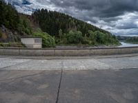 concrete walkway with trees and fenced in area on opposite sides of the road and one side of the road