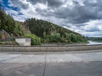 concrete walkway with trees and fenced in area on opposite sides of the road and one side of the road