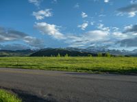 a lone country road is in the countryside area with mountains on both sides and barbed fence between the two sides