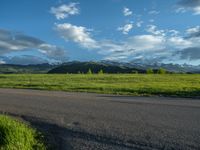 a lone country road is in the countryside area with mountains on both sides and barbed fence between the two sides