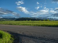 a lone country road is in the countryside area with mountains on both sides and barbed fence between the two sides