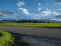 a lone country road is in the countryside area with mountains on both sides and barbed fence between the two sides