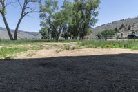 there is a small field and a fenced in area near some trees and brush