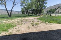 there is a small field and a fenced in area near some trees and brush