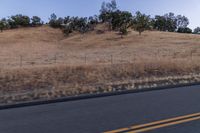 a couple of people riding bikes on a road by the side of a hill on a clear day