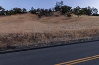 a couple of people riding bikes on a road by the side of a hill on a clear day