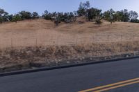 a couple of people riding bikes on a road by the side of a hill on a clear day