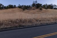 a couple of people riding bikes on a road by the side of a hill on a clear day