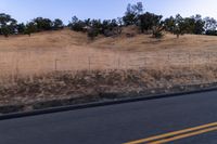 a couple of people riding bikes on a road by the side of a hill on a clear day