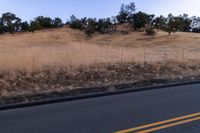 a couple of people riding bikes on a road by the side of a hill on a clear day