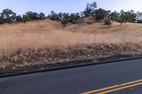 a couple of people riding bikes on a road by the side of a hill on a clear day