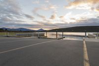 empty parking lot with view across the lake at sunset, with ramp and pier in the foreground