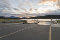 empty parking lot with view across the lake at sunset, with ramp and pier in the foreground