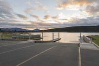 empty parking lot with view across the lake at sunset, with ramp and pier in the foreground