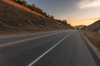 view of a highway with a hillside in the background as seen from a vehicle on a road trip