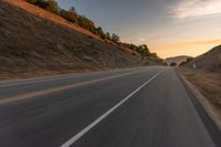 view of a highway with a hillside in the background as seen from a vehicle on a road trip