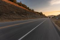 view of a highway with a hillside in the background as seen from a vehicle on a road trip