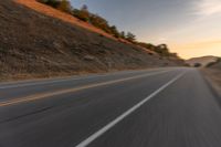 view of a highway with a hillside in the background as seen from a vehicle on a road trip