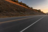 view of a highway with a hillside in the background as seen from a vehicle on a road trip