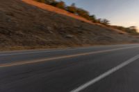 view of a highway with a hillside in the background as seen from a vehicle on a road trip