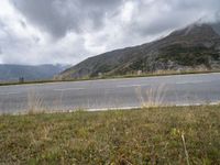 an open road with some mountains behind it on a cloudy day - photo c - print