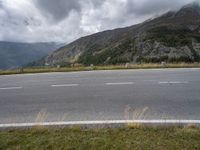 an open road with some mountains behind it on a cloudy day - photo c - print