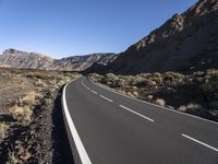 empty paved road going through the rocky mountainside during winter months, outdoors near desert, high