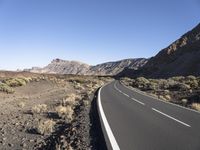 empty paved road going through the rocky mountainside during winter months, outdoors near desert, high