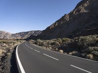 empty paved road going through the rocky mountainside during winter months, outdoors near desert, high