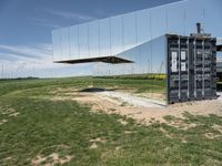 an abstract, mirrored structure on the outside of a building sitting in the grass in a field