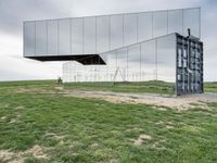 a man rides his bike next to a building made out of mirrored panels at the top