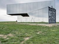 a man rides his bike next to a building made out of mirrored panels at the top