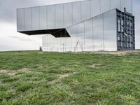 a man rides his bike next to a building made out of mirrored panels at the top