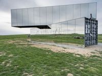 a man rides his bike next to a building made out of mirrored panels at the top