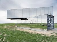 a man rides his bike next to a building made out of mirrored panels at the top