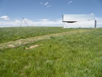 an old barn stands on a field of grass near a telephone pole under a blue sky