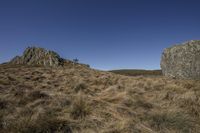 large, grassy hill with rock on the top and sky in the back ground below