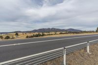 a large open area near the highway with hills in the background and a fence between it