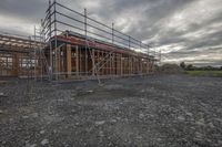 a home is under construction in a field of gravel and rocks in an overcast sky