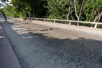 a concrete bridge over a city street with trees in the background behind it and a man riding his bike