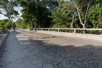 a concrete bridge over a city street with trees in the background behind it and a man riding his bike