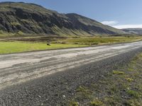 a dirt road running down some mountains with grass and rocks on both sides of it