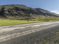 a dirt road running down some mountains with grass and rocks on both sides of it