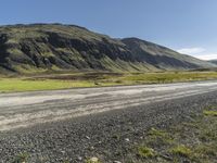 a dirt road running down some mountains with grass and rocks on both sides of it