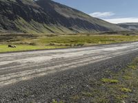 a dirt road running down some mountains with grass and rocks on both sides of it