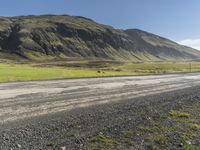 a dirt road running down some mountains with grass and rocks on both sides of it