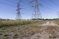 electricity towers with dirt roads and grass in a field on the outskirts of the town