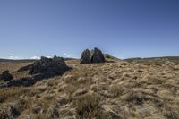 rocks and grass in the field in front of a bright blue sky and clouds on a sunny day