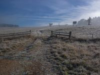 a gate surrounded by frosted grass and a fence to access it into the field