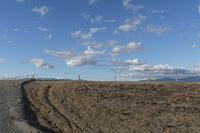 an empty road through a barren landscape with windmills in the distance under blue sky